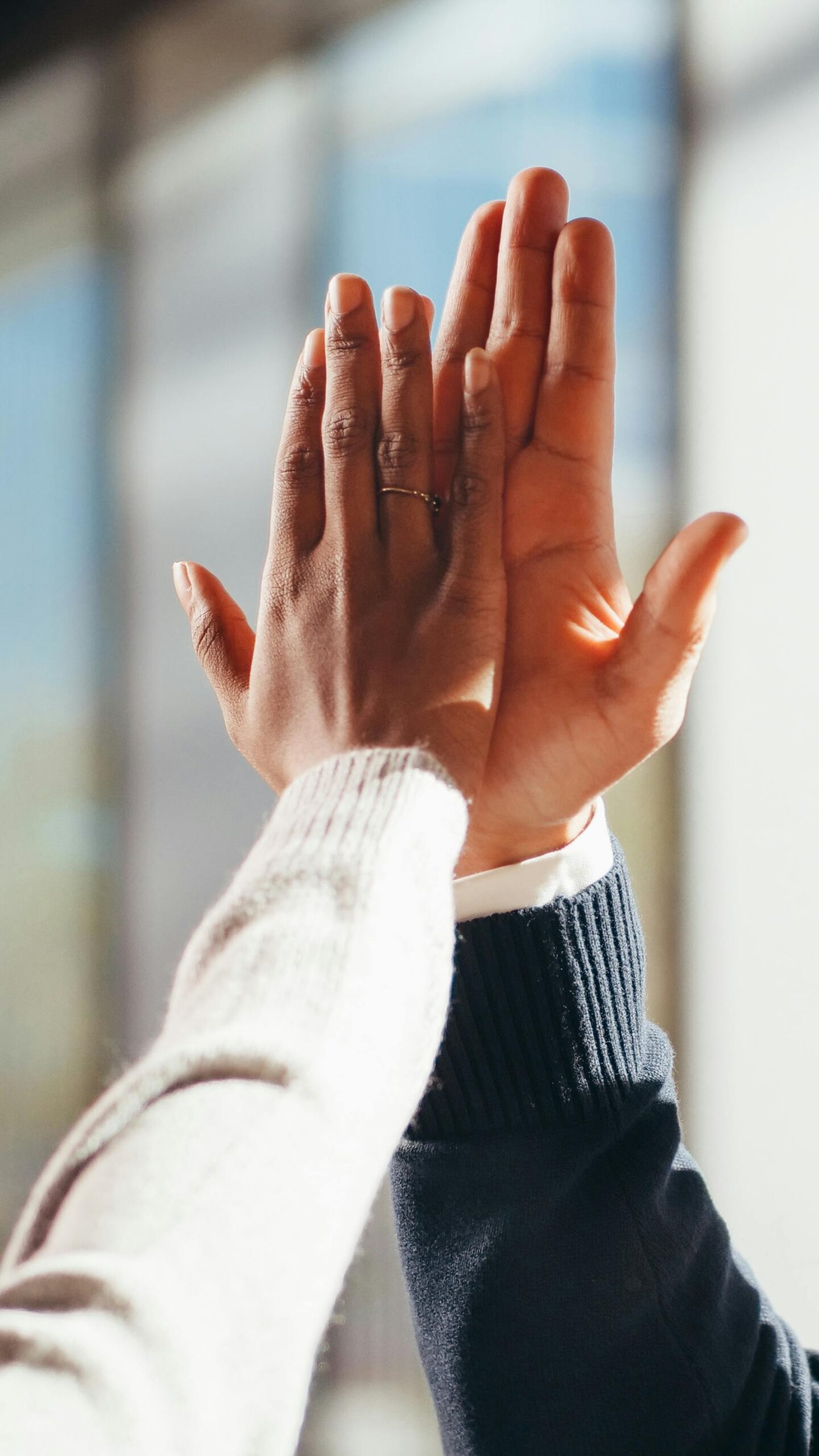 Close-up of two diverse people's hands high-fiving in a gesture of success and teamwork.